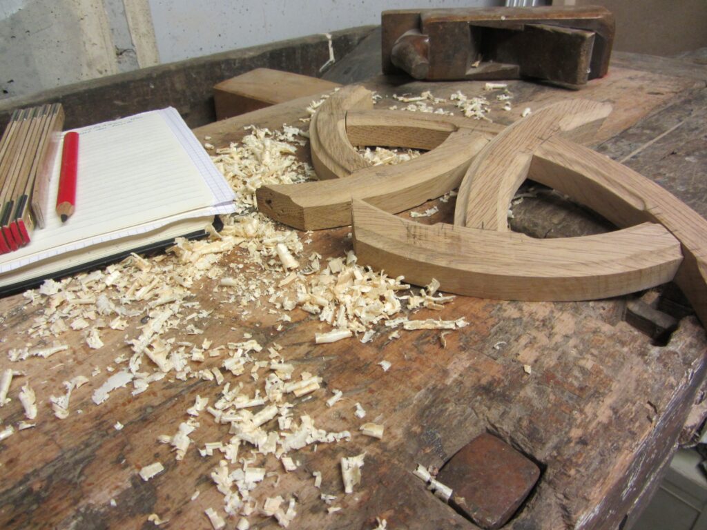 Pièces de bois massif en cours de fabrication sur établi d'atelier, copeaux et travail artisanal